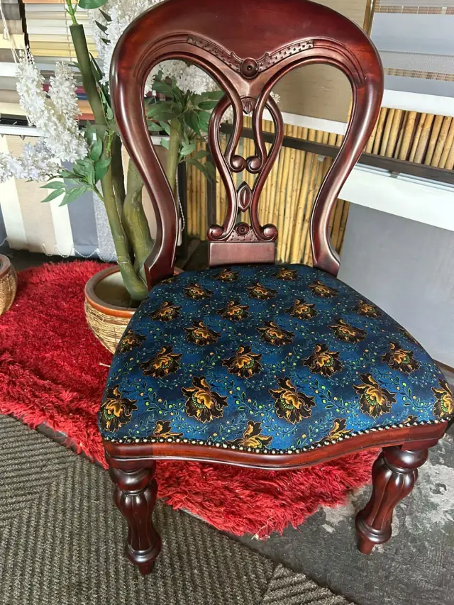 A carved balloon-back chair with a patterned seat
