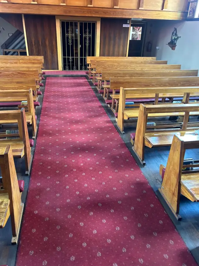 Pews with red seat cushions along a church aisle