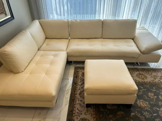 A cream leather corner sofa and ottoman