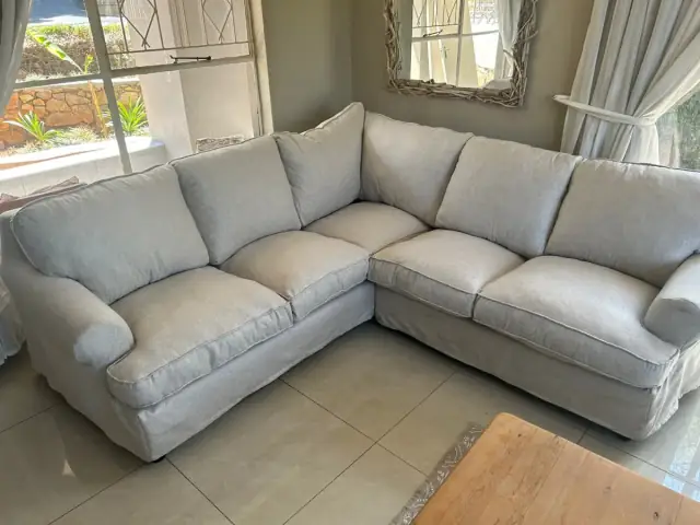 A grey corner sofa with loose covers