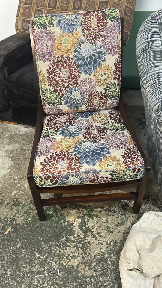 A patio chair with floral cushions on a wooden frame