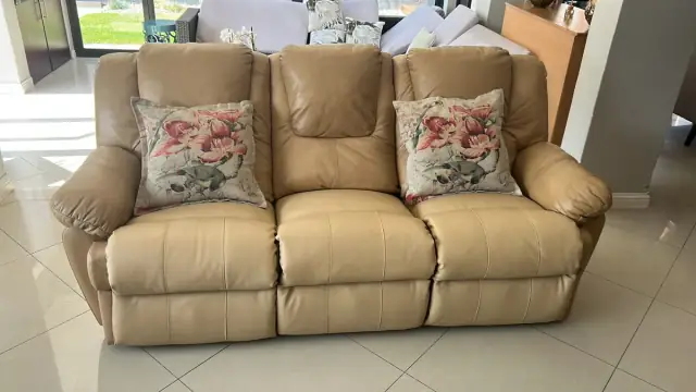 The cream leather recliner at home, with floral cushions