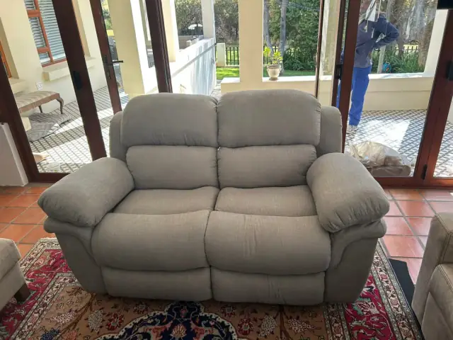 A grey fabric two-seater recliner