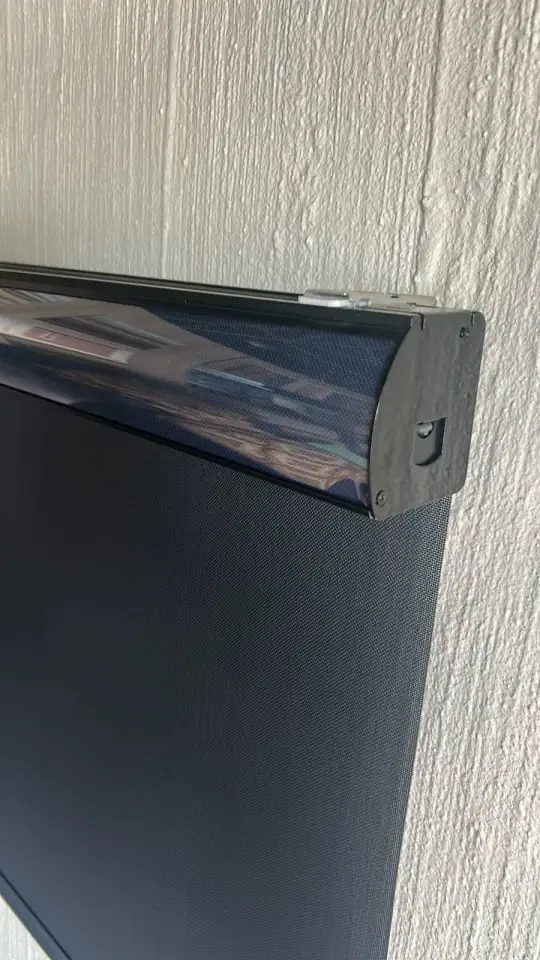 A roller blind in a dark fabric, with its cassette