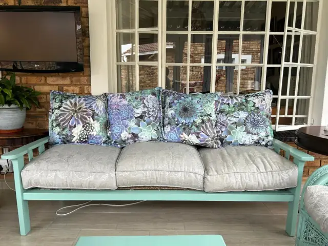 A sofa with grey seat cushions and succulent-print scatter cushions