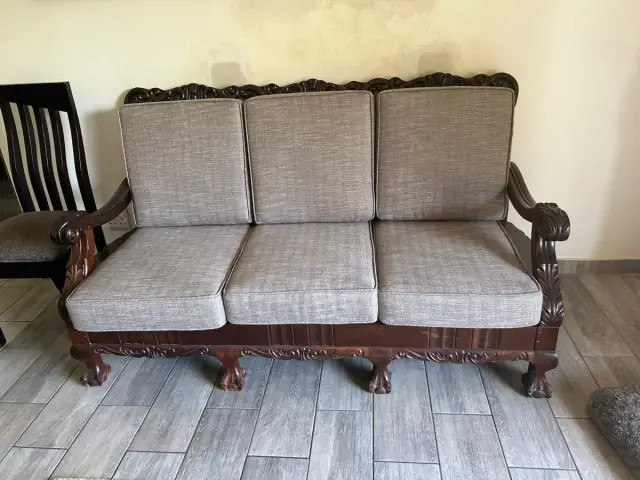 A three-seater with a carved wooden frame, in a grey weave