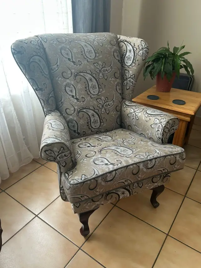 A wingback chair in a grey paisley